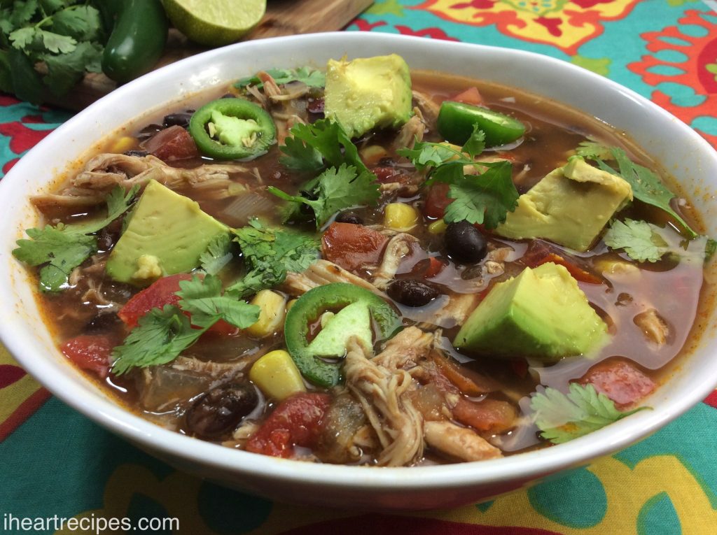 Tex Mex Chicken Soup served in a white bowl on top of a colorful tablecloth. 