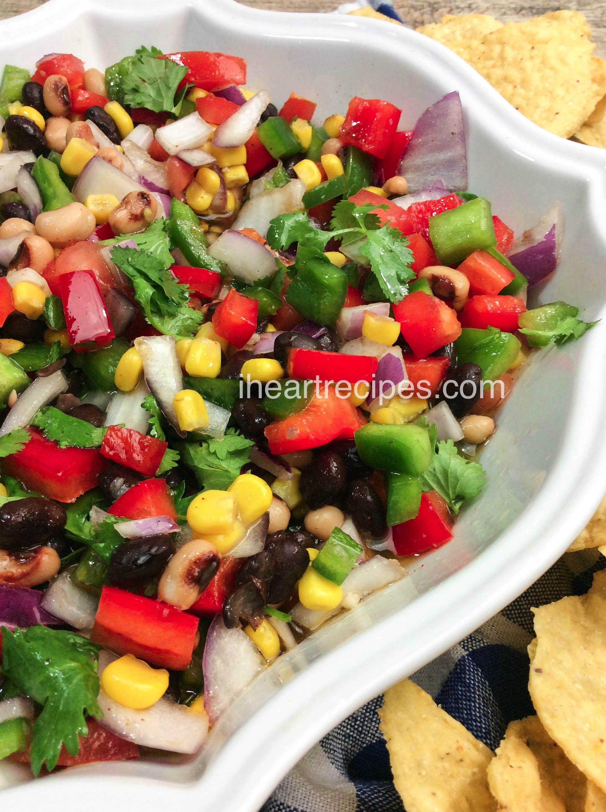 A classic white serving dish filled with flavorful Texas Caviar, garnished with cilantro and served alongside tortilla chips is an irresistible snack! 