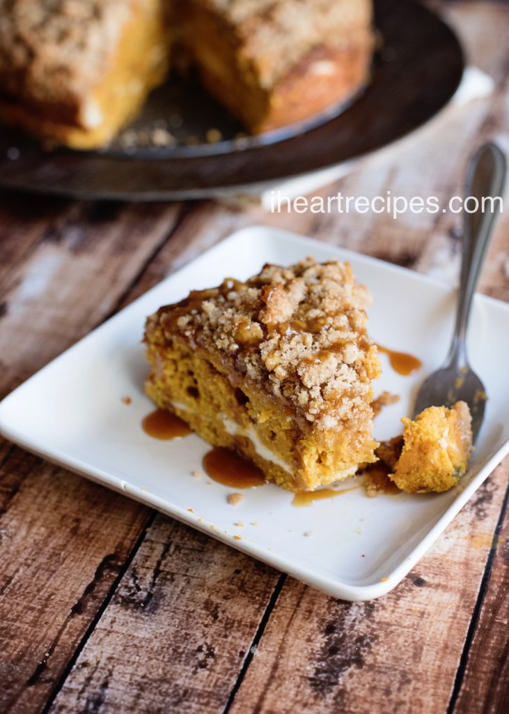 This slice of caramel pumpkin coffee cake has a fluffy cream cheese filling and is drizzled with a sweet caramel syrup. A bite of coffee cake rests on a silver fork. 