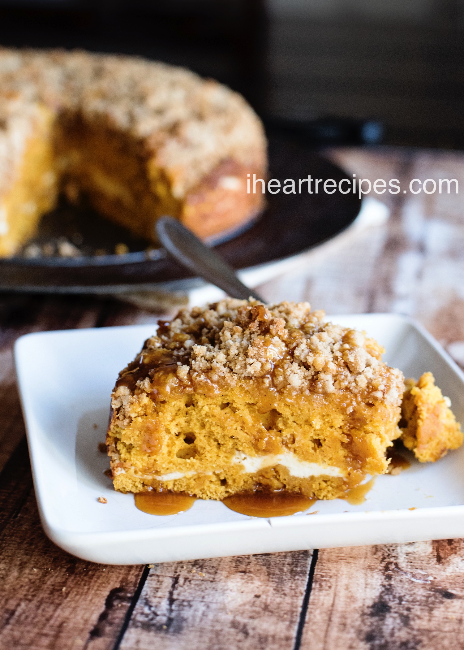 A sweet and delicious slice of caramel pumpkin cake, topped with sweet crumble topping and caramel syrup on a white plate. 