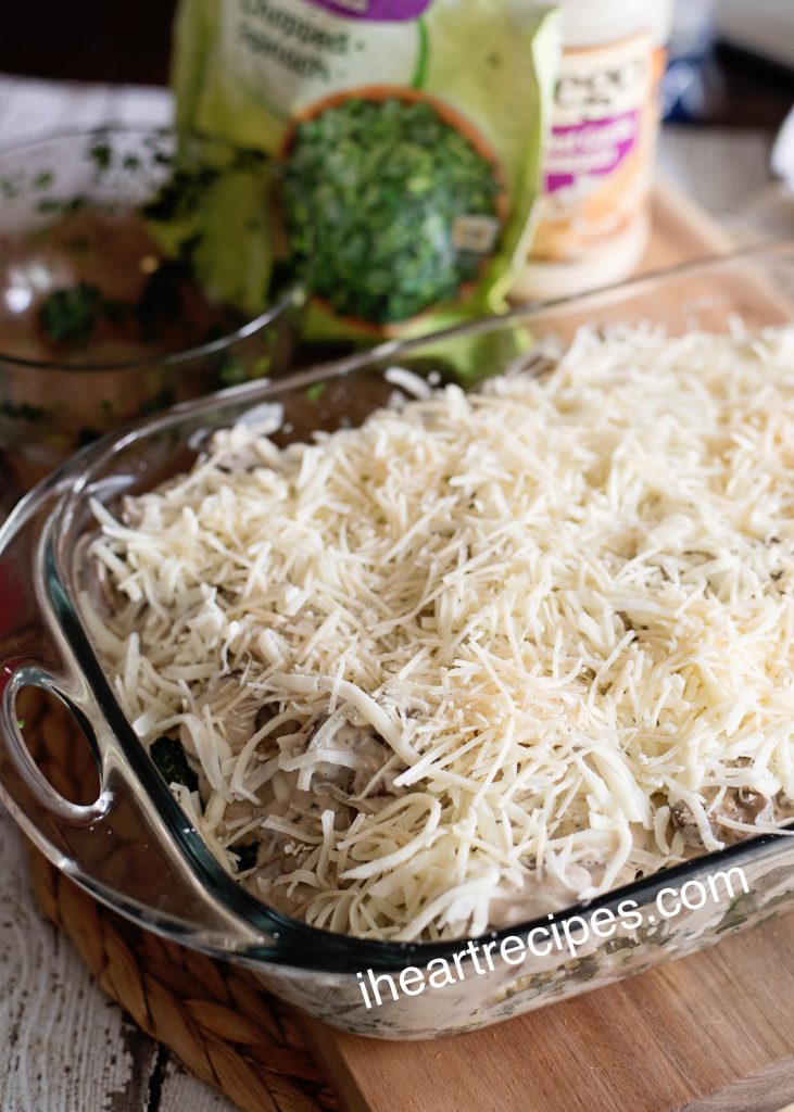 A clear glass casserole dish is filled with a homemade vegetarian vegetable lasagna, made with a creamy white sauce and topped with shredded parmesan cheese.