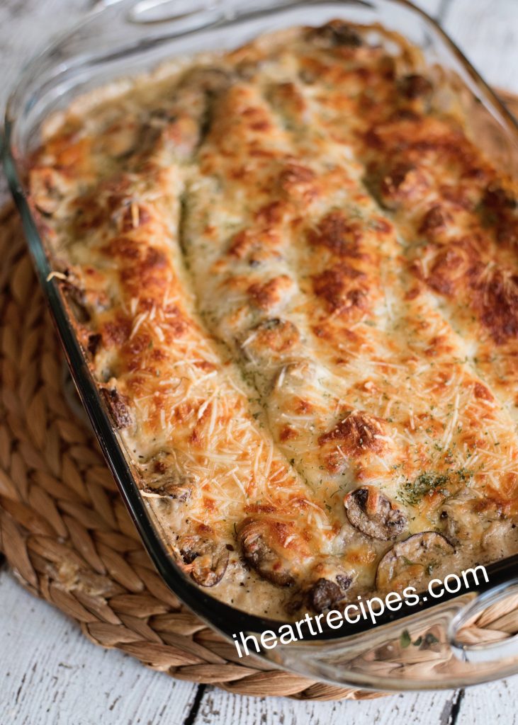 A glass casserole dish is filled with a freshly baked vegetable lasagna, topped with broiled golden-brown shredded cheese.