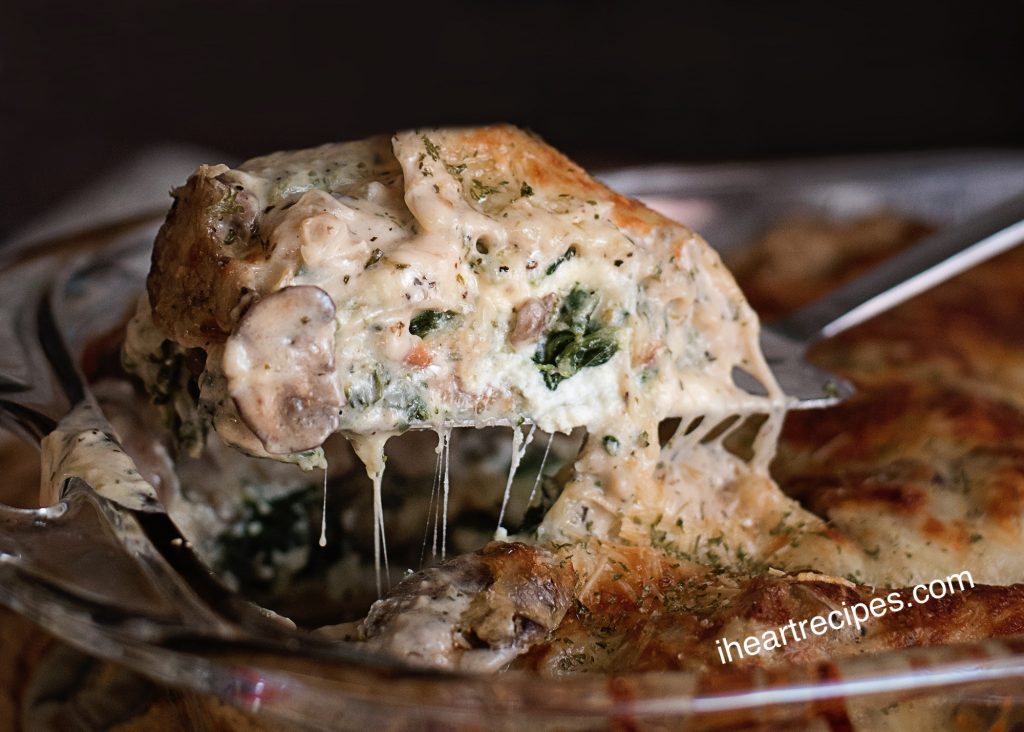 A creamy slice of vegetable lasagna, made with a cheesy white sauce layered between lasagna noodles and vegetables including spinach and mushrooms.