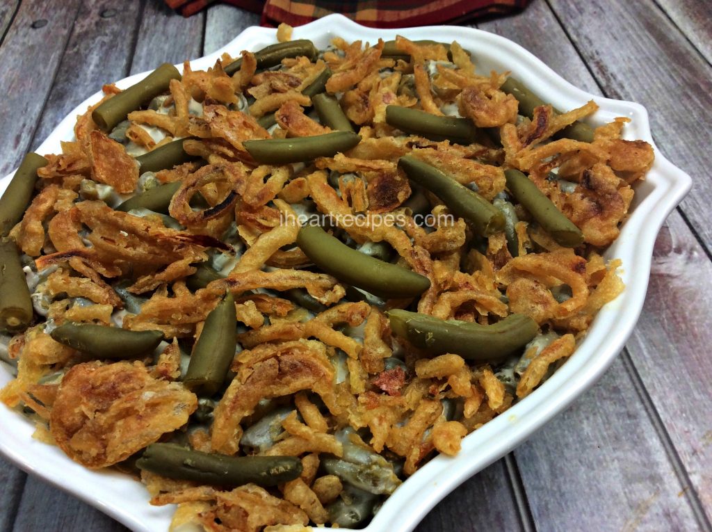 A white casserole dish filled with fresh baked green bean casserole topped with crispy French-fried onions.