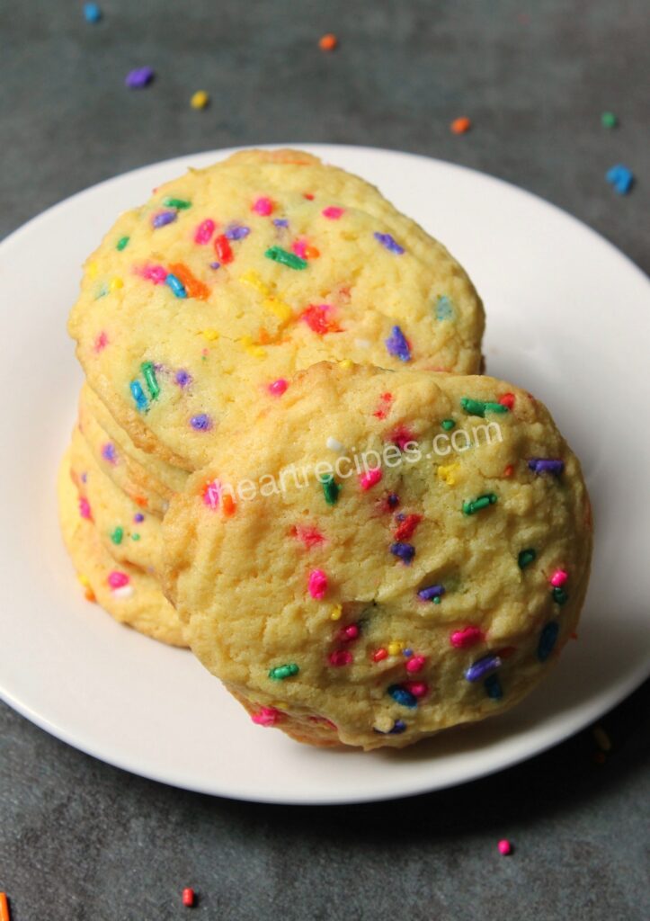 A close up of golden cake mix confetti cookies sprinkled with rainbow candies. 