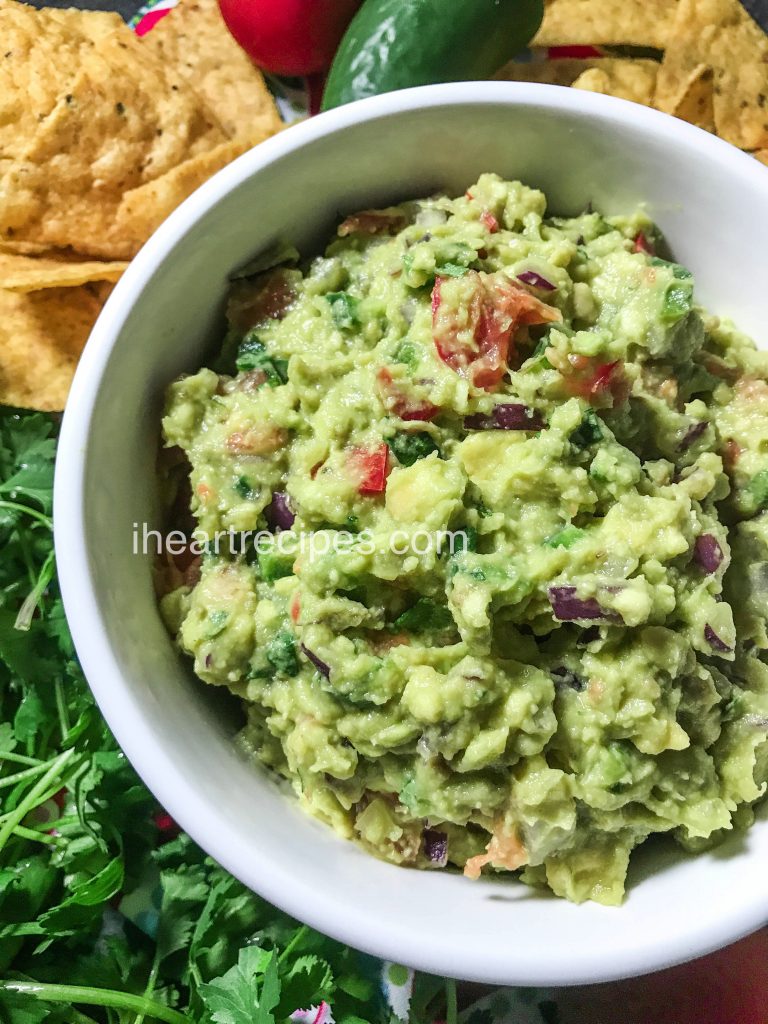 In this bowl of delicious, easy homemade guacamole, you can see the crisp, red onions, sweet tomatoes, and tender avocados that make this a crowd-pleaser at any party.