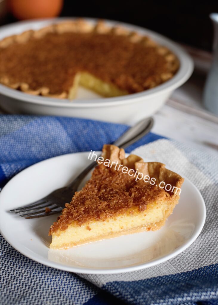 A single slice of chess pie served on a small white plate with a silver fork. 