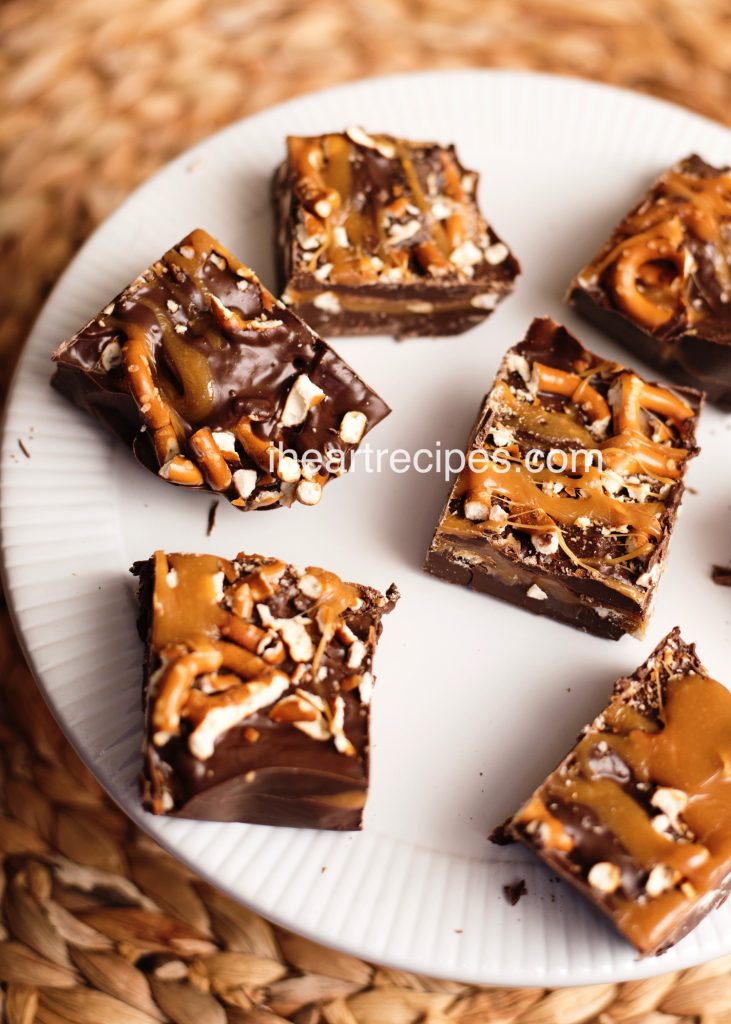 A white plate loaded with deliciously sweet and salty bars drizzled with caramel.