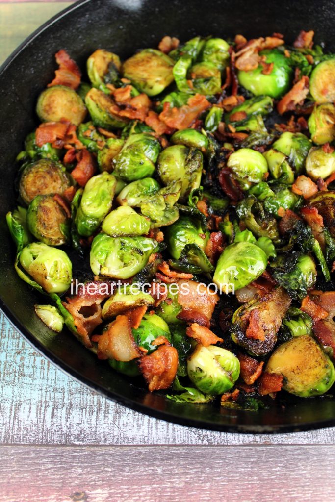 A close up of halved roasted Brussels sprouts and large bacon chunks coated in a shiny balsamic glaze. This is a simple, delicious side dish to serve with dinner