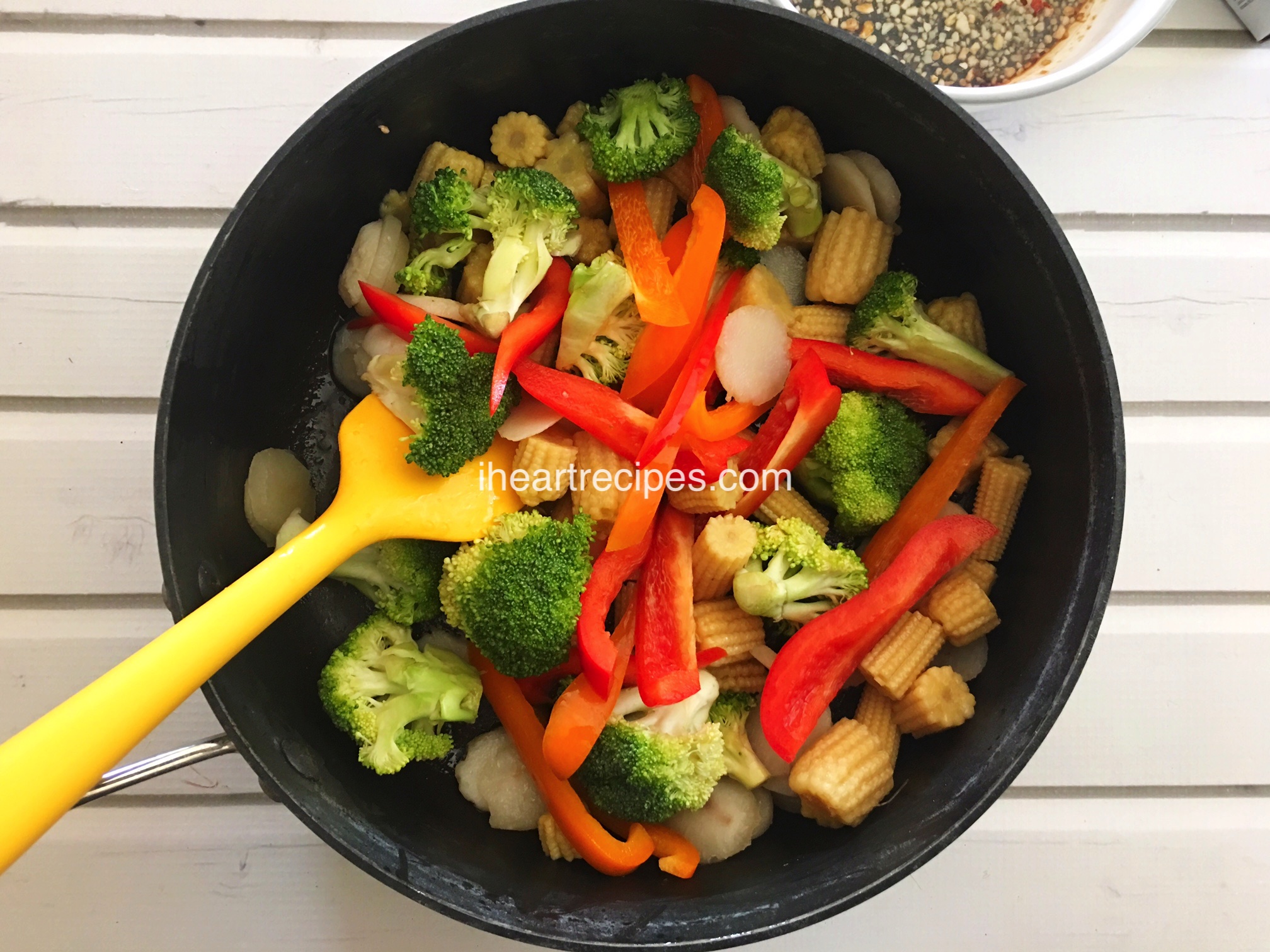 A large bowl of fresh veggies for a vegetable stir fry -- peppers, broccoli, baby corns, and water chestnuts.