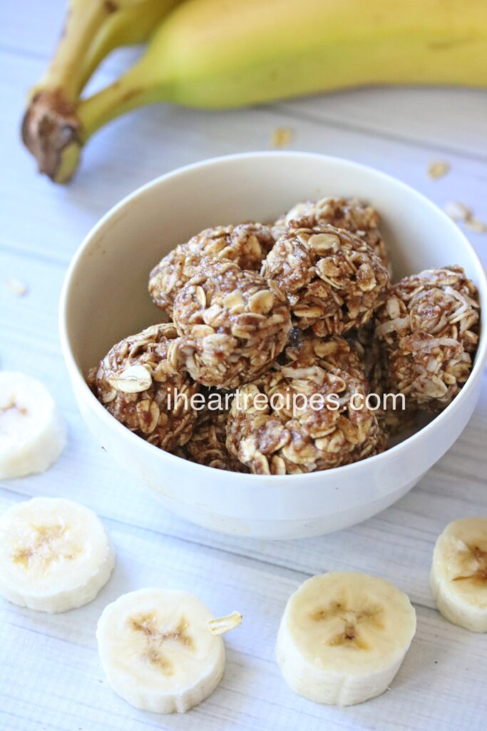 A bowl of healthy no-bake banana energy bites made with peanut butter and oats, surrounded by slices of fresh banana.