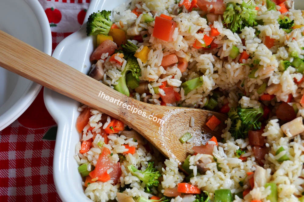 An overhead image of a casserole dish filled with cold rice salad and a wooden serving spoon.