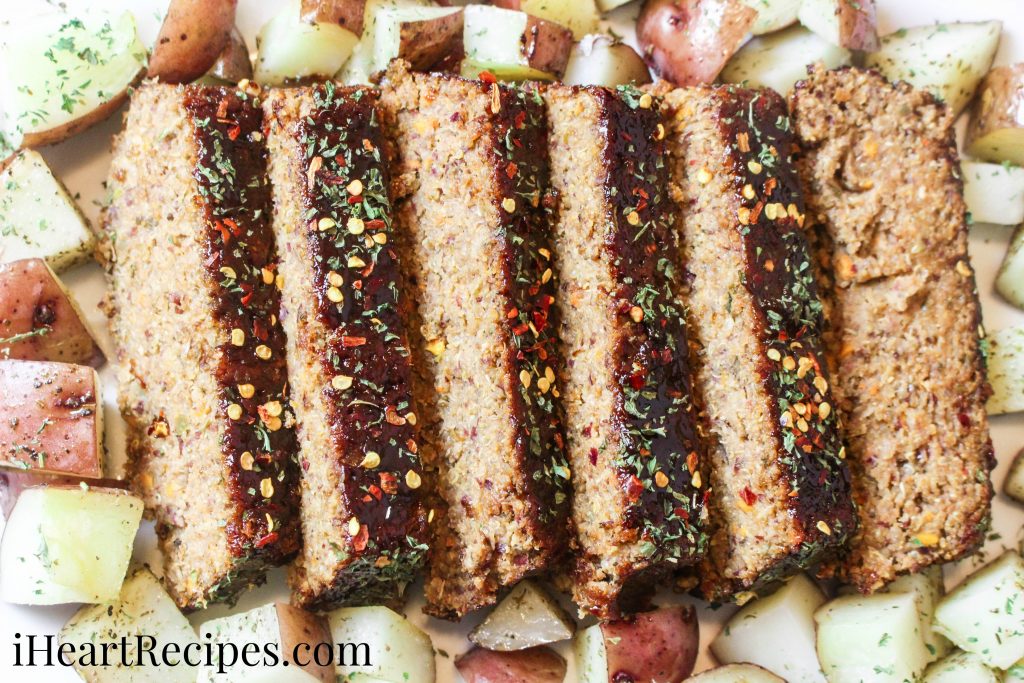 Slices of savory vegetarian meatloaf with a side of red potatoes served on a white plate. Add a salad for a delicious meal!