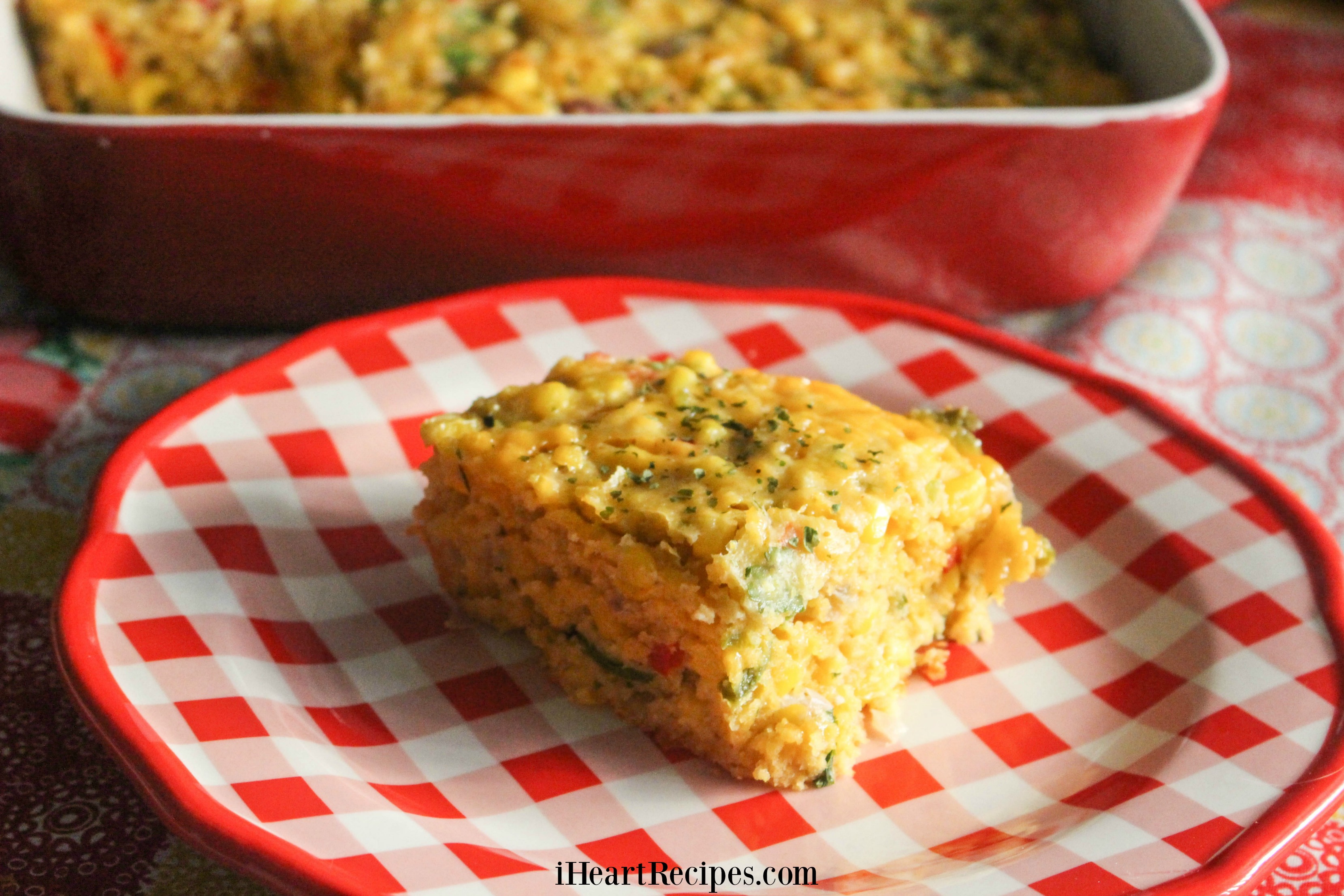 A delicious square of tex mex corn casserole served on a red and white plaid plate. 