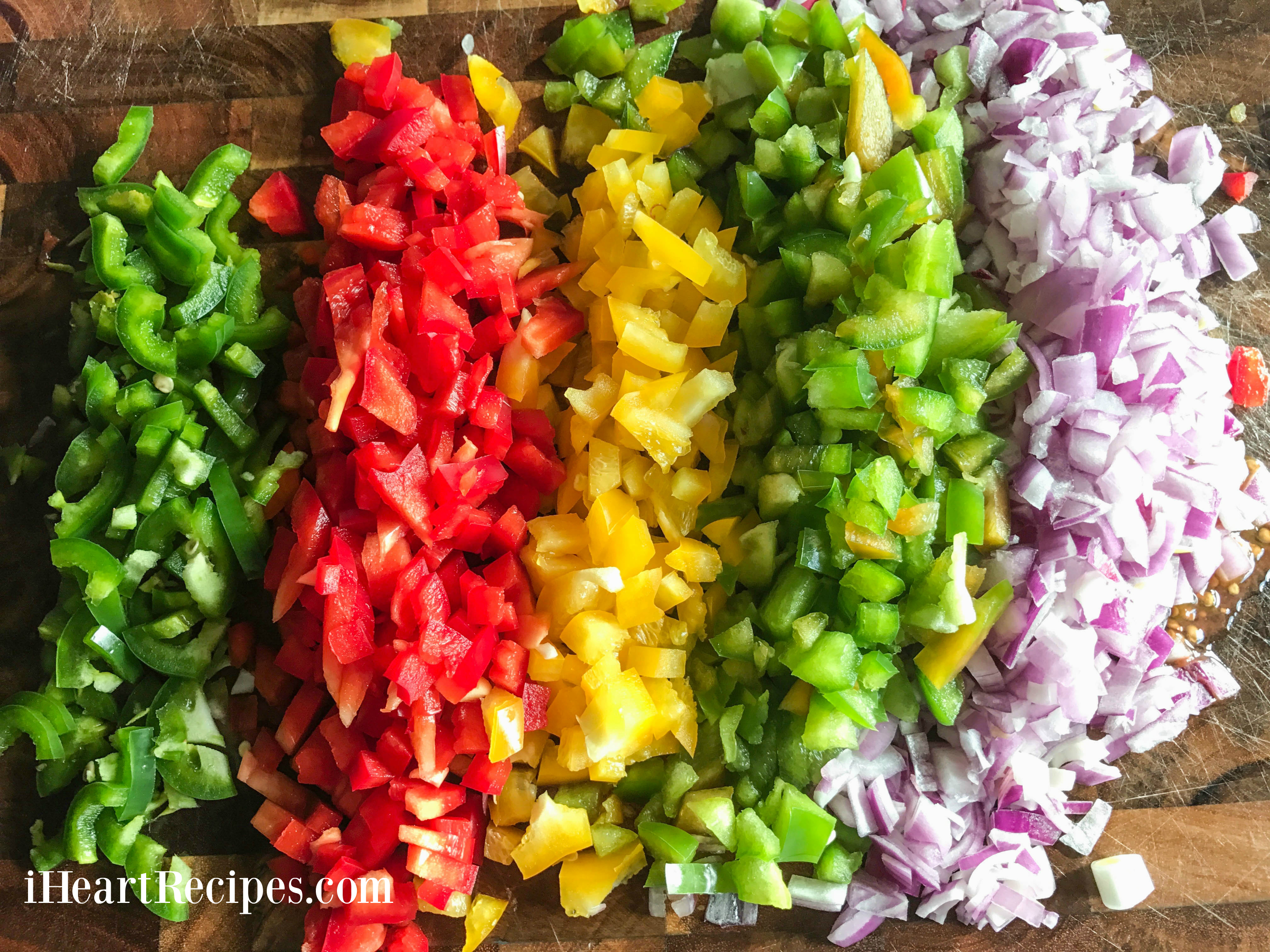 A rainbow of diced vegetables on a wooden chopping block. 