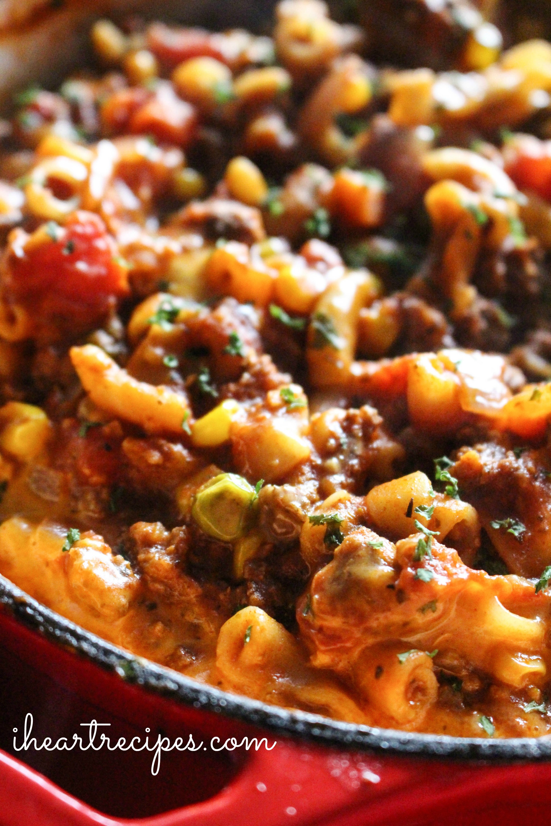 Creamy old fashioned beef goulash garnished with savory herbs simmering in red skillet. This recipe will surely become a family favorite!