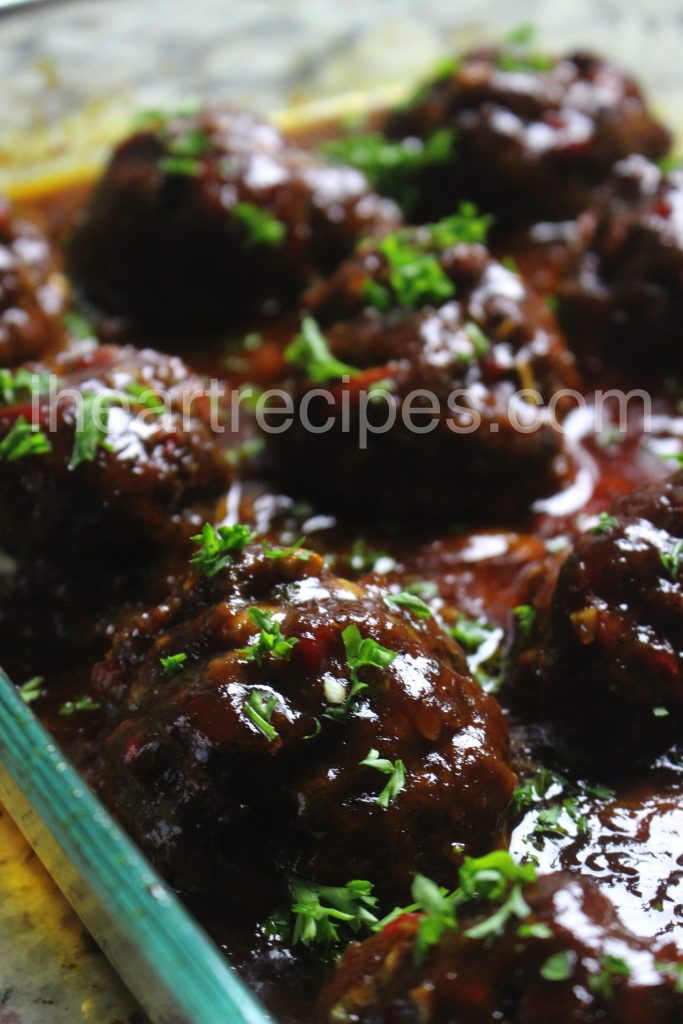 A panful of BBQ Meatloaf Meatballs smothered in sauce and garnished with fresh parsley. 