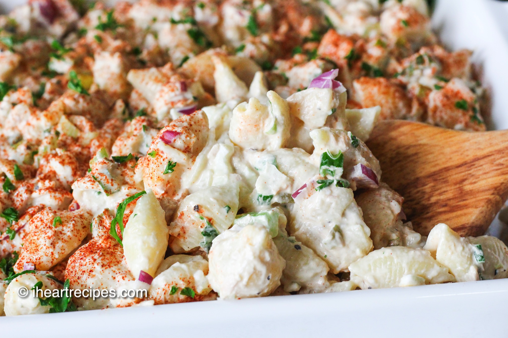 A close-up image of creamy tuna pasta salad—cooked pasta mixed with veggies and seasonings in a creamy mayo dressing.