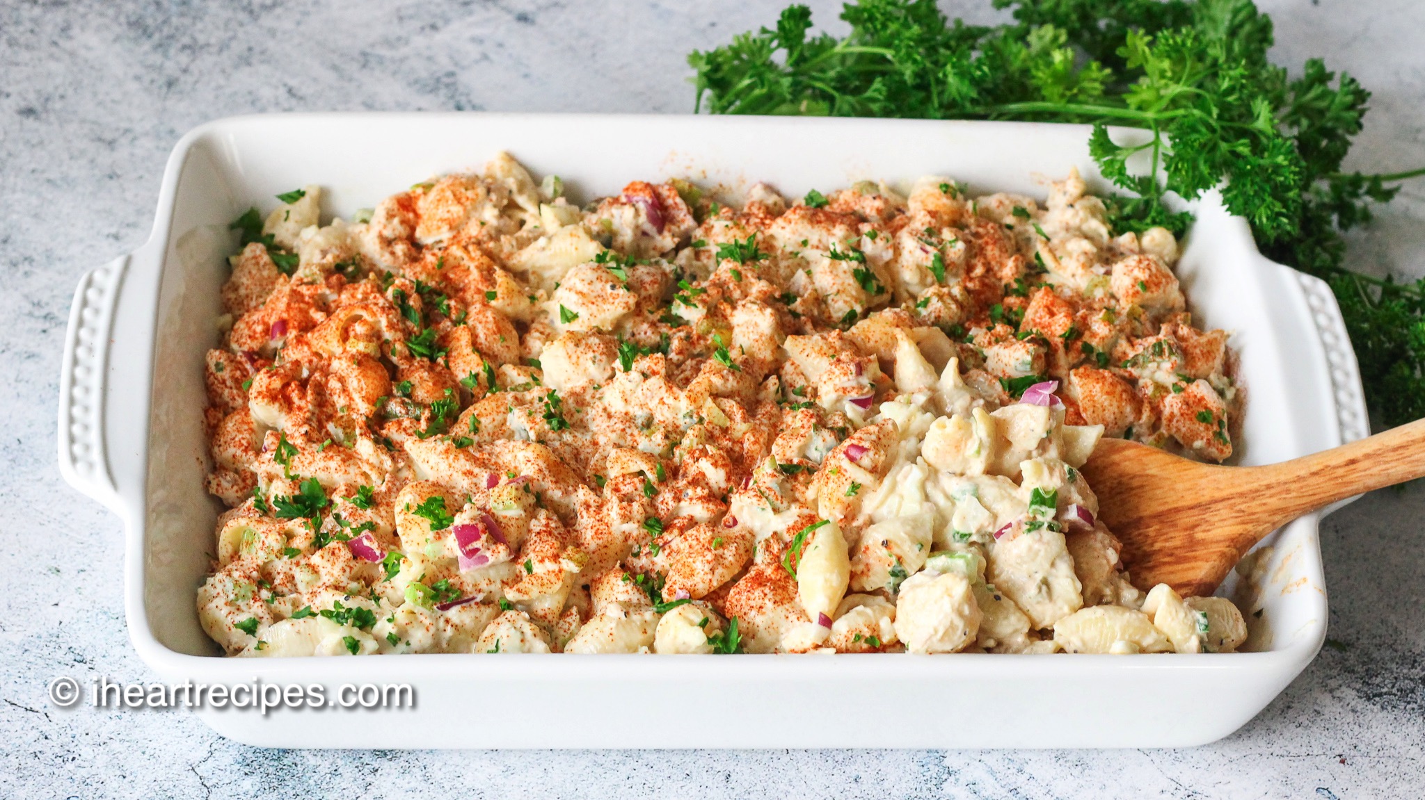 A white casserole dish filled with creamy tuna macaroni salad—a creamy pasta salad made with flaky tuna, vegetables, seasonings, and a mayonnaise dressing.