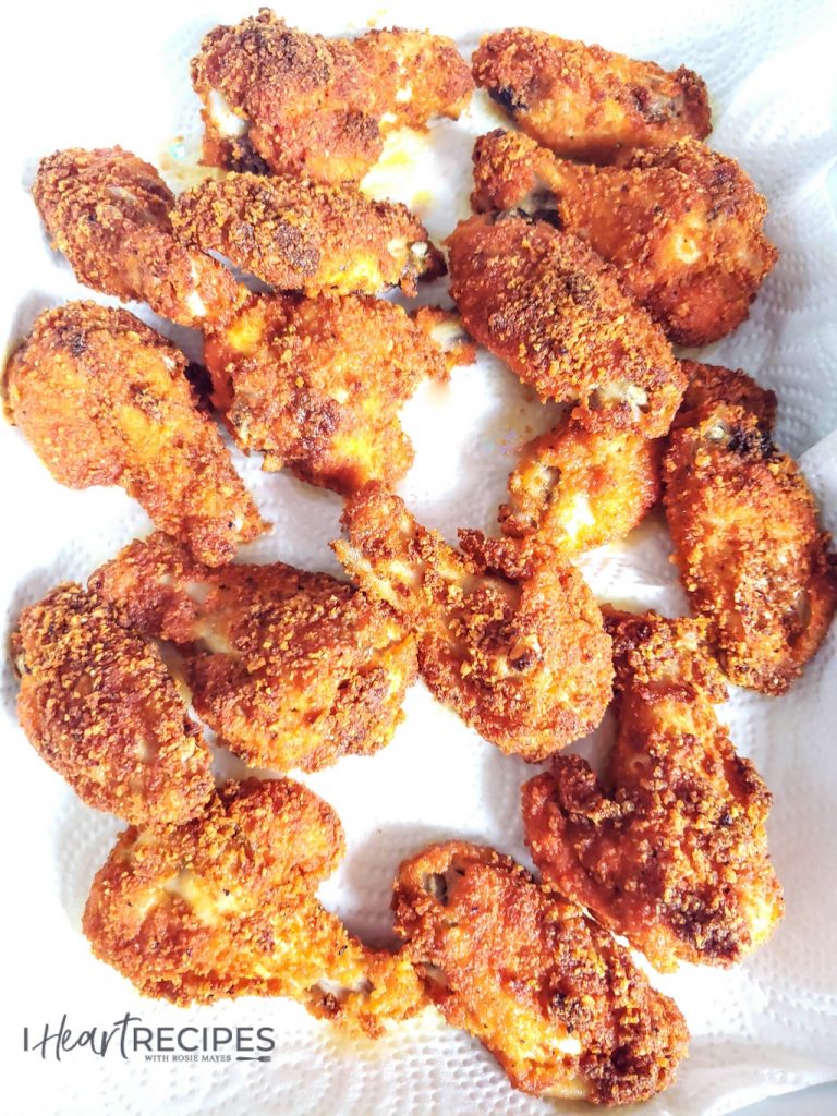 Pieces of spicy keto fried chicken laid out on paper towels; coated with a golden-brown low-carb breading make from spicy pork rinds and oven-baked for a crispy fried-chicken taste.