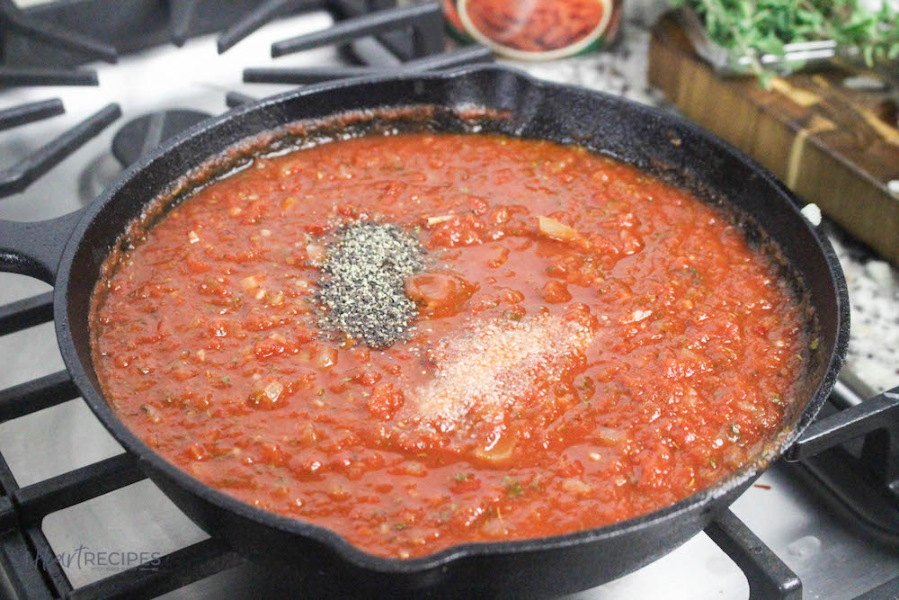 A simmering pot of homemade marinara sauce, seasoned with simple salt and pepper and other delicious spices