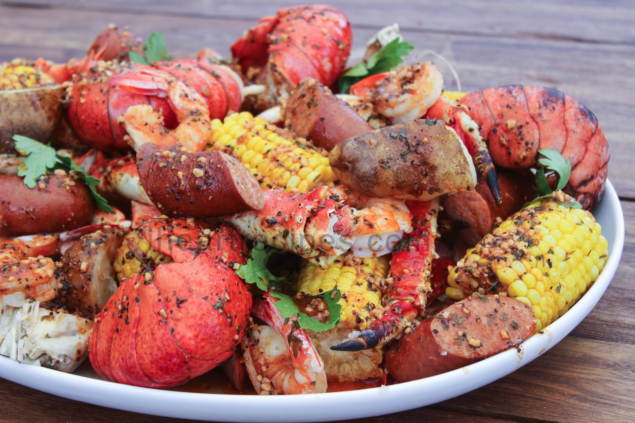 A platterful of lobster, crab, shrimp, corn, and potatoes covered in zesty garlic butter. This homemade seafood boil has all your favorite seafood and Creole flavors.