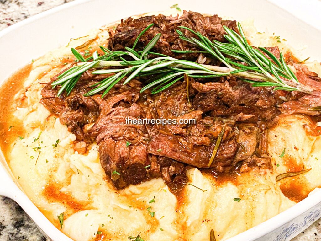 Fall off the bone tender smothered beef roast served over a bed of creamy herb mashed potatoes