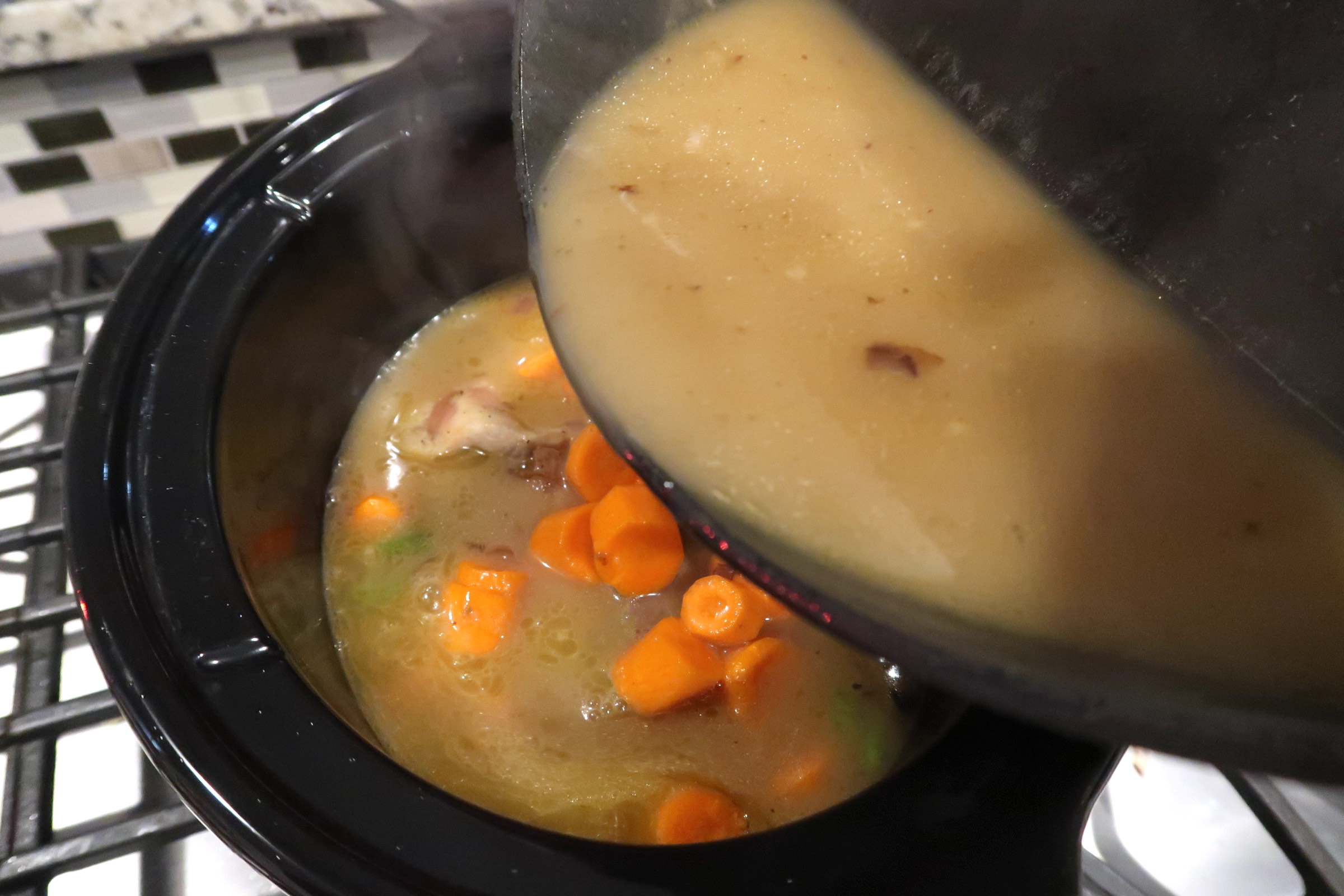 Pouring golden homemade chicken stock over the ingredients of homemade chicken stew.