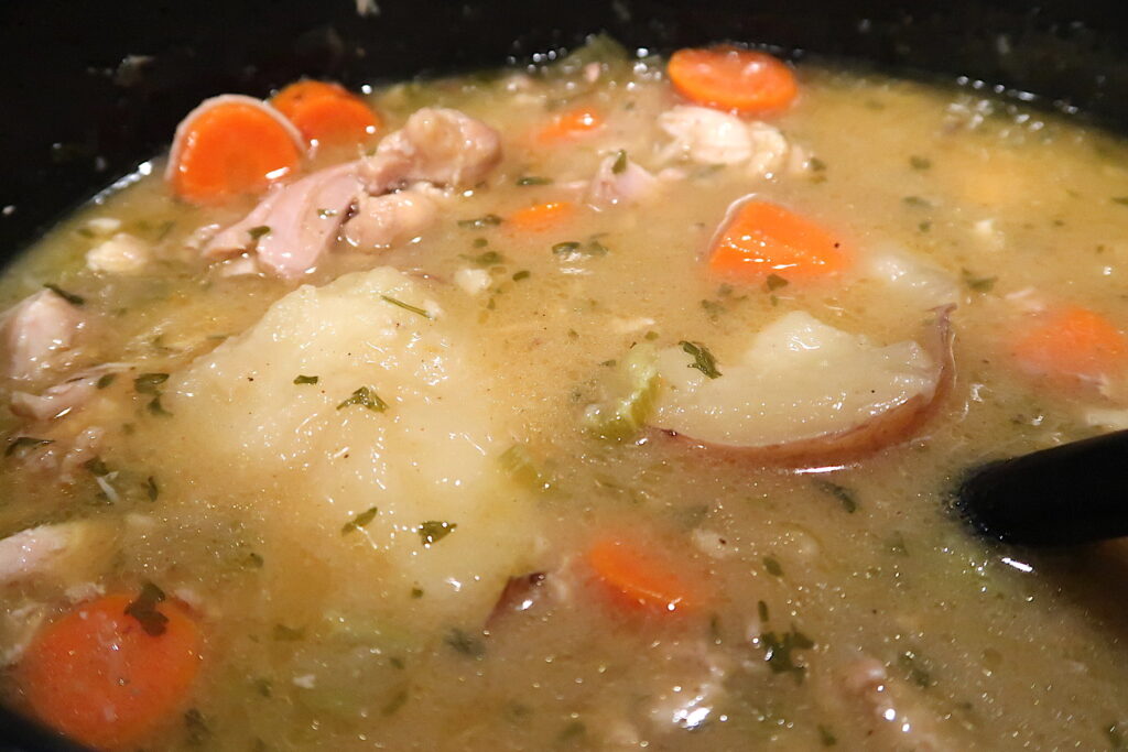 A combination of tender chicken,  tender carrots, potatoes, celery and more floating in golden seasoned gravy. 