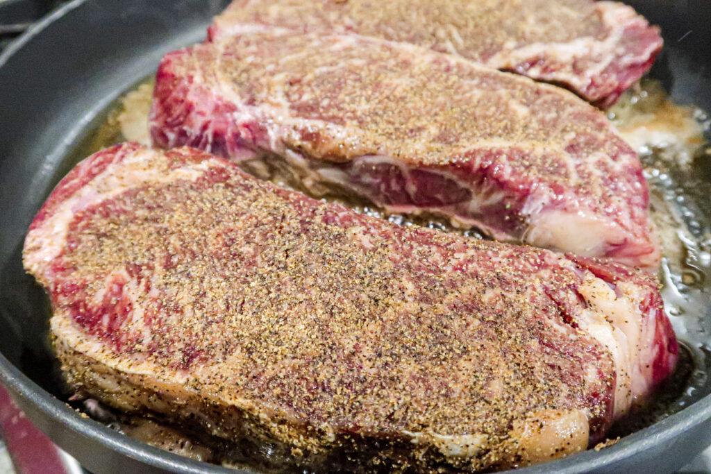 Wagyu steaks sit in a hot griddle, perfectly coated in Rosamae's steak seasoning.