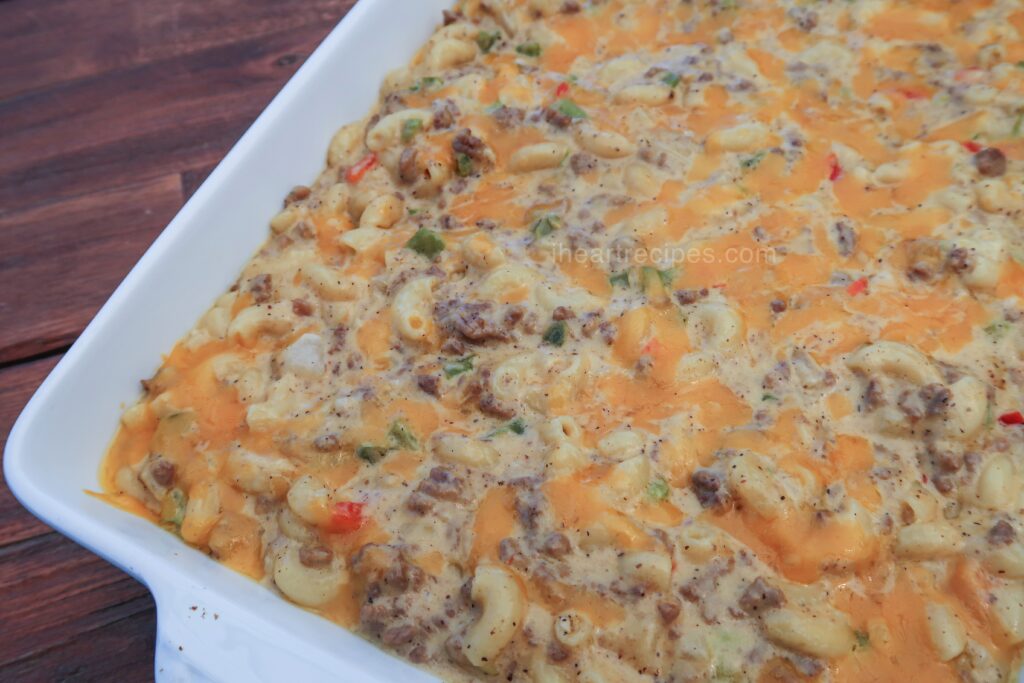 Cheesy, savory Homemade Cheeseburger Hamburger Helper with tender pasta and veggies fills a white bake dish set on a wooden table. 