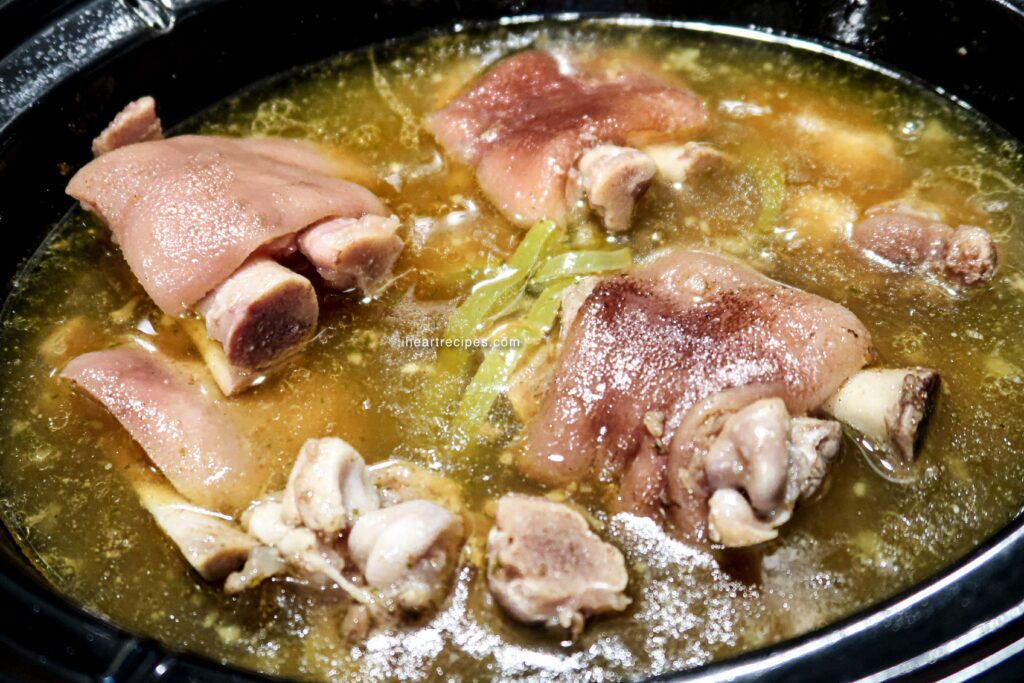 Tender pigs feet slow cooked in a rich broth in a crock pot.