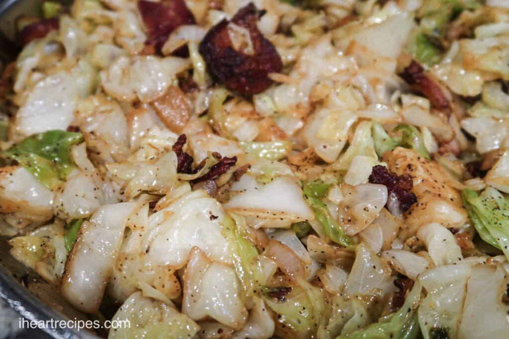 A close up look at skillet-fried cabbage with bacon, onions, and spices.