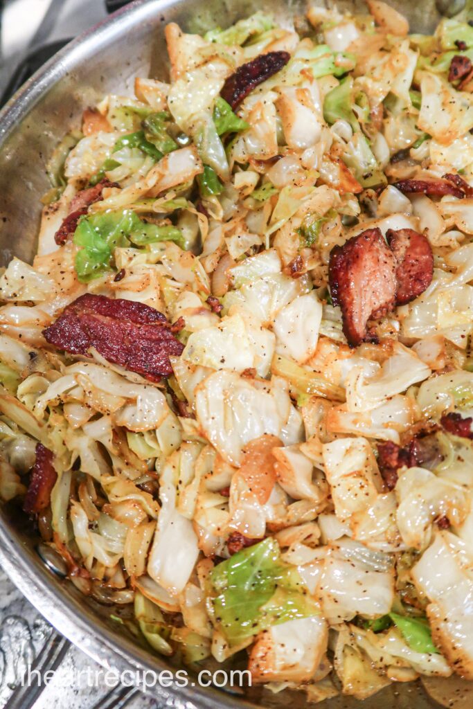 A close up look at a skillet of crispy pan-friend cabbage with bacon and spices. 
