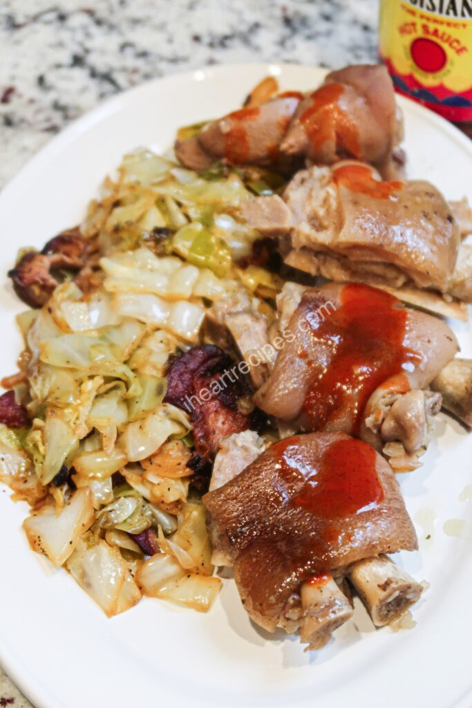 Slow cooked southern-style pigs feet served with fried cabbage and hot sauce.