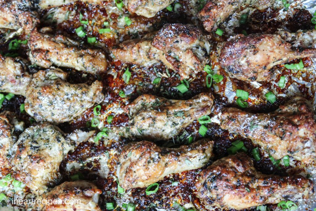 A pan full of delicious baked garlic parmesan chicken wings, garnished with grated parmesan and chopped green onions.