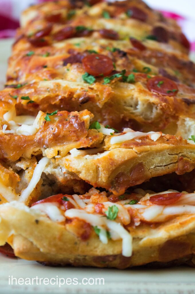 A close up look at the flakey layers of pepperoni pull-apart bread, made with store-bought pizza dough, pizza sauce, cheese, and mini pepperonis.