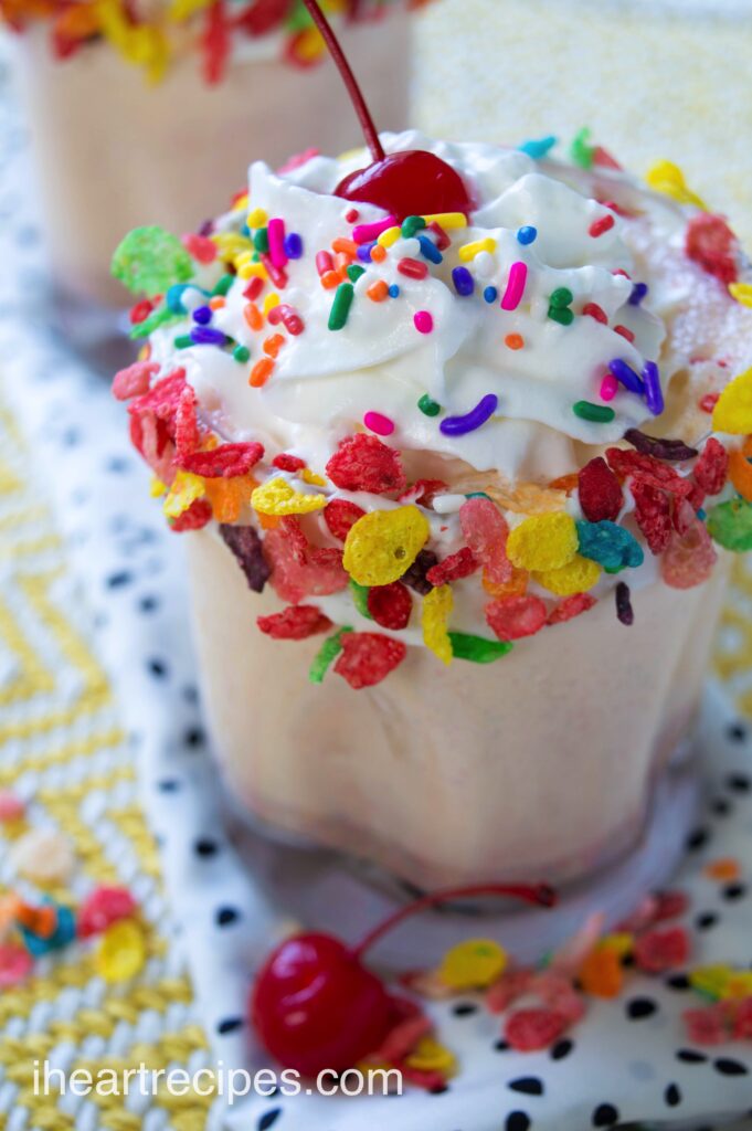 A sweet Fruity Pebbles milkshake made with vanilla ice cream and Fruity Pebbles cereal, topped with whipped cream, sprinkles, and colorful Fruity Pebbles cereal.