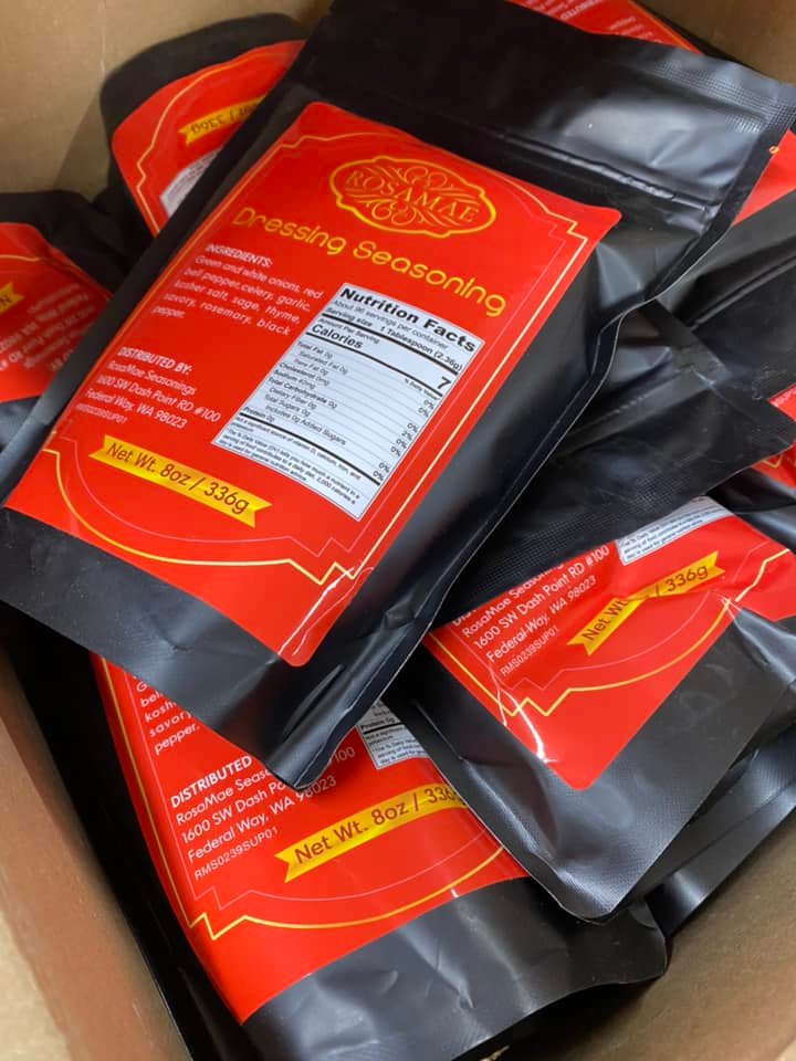 Packages of Rosamae dressings seasoning in a box. The packages of seasoning mix come in black pouches with red labels.