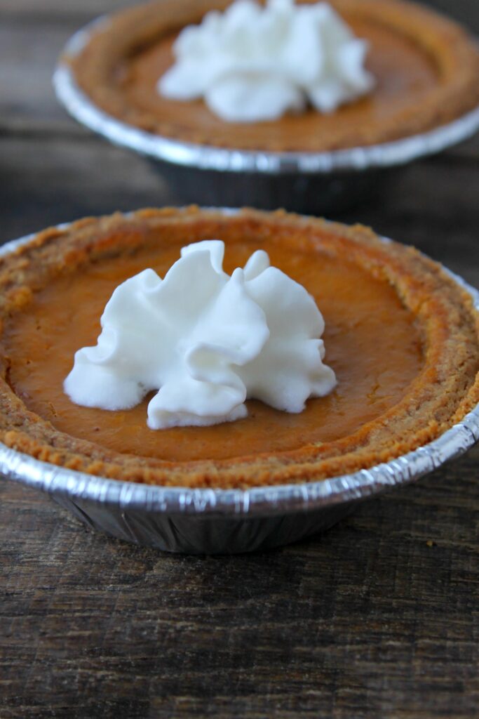 A perfectly-sized mini pumpkin pie topped with a dollop of whipped cream - the perfect Fall dessert!