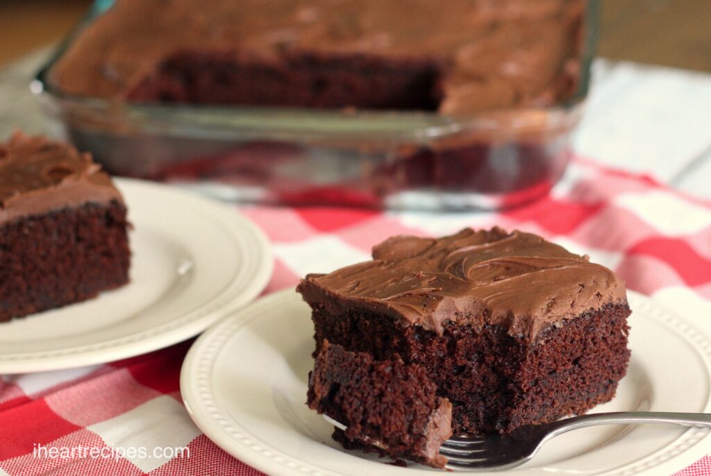 A slice of moist sour cream chocolate cake with creamy chocolate frosting, served on white plates.