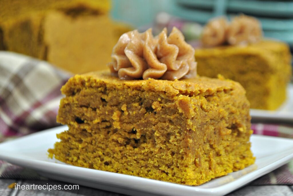 A slice of super moist pumpkin cornbread, topped with a dollop of homemade spiced honey butter, and served on a square white plate.