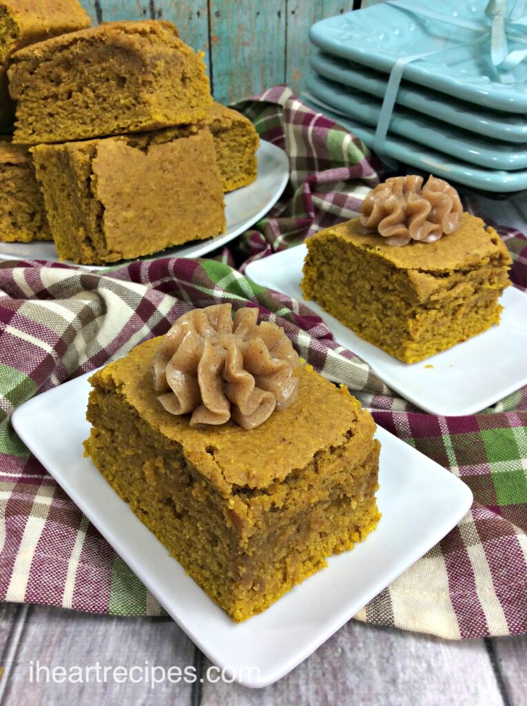 Two plated slices of pumpkin cornbread, topped with a homemade spiced honey butter, and a third plate stacked with fresh slices of pumpkin cornbread.