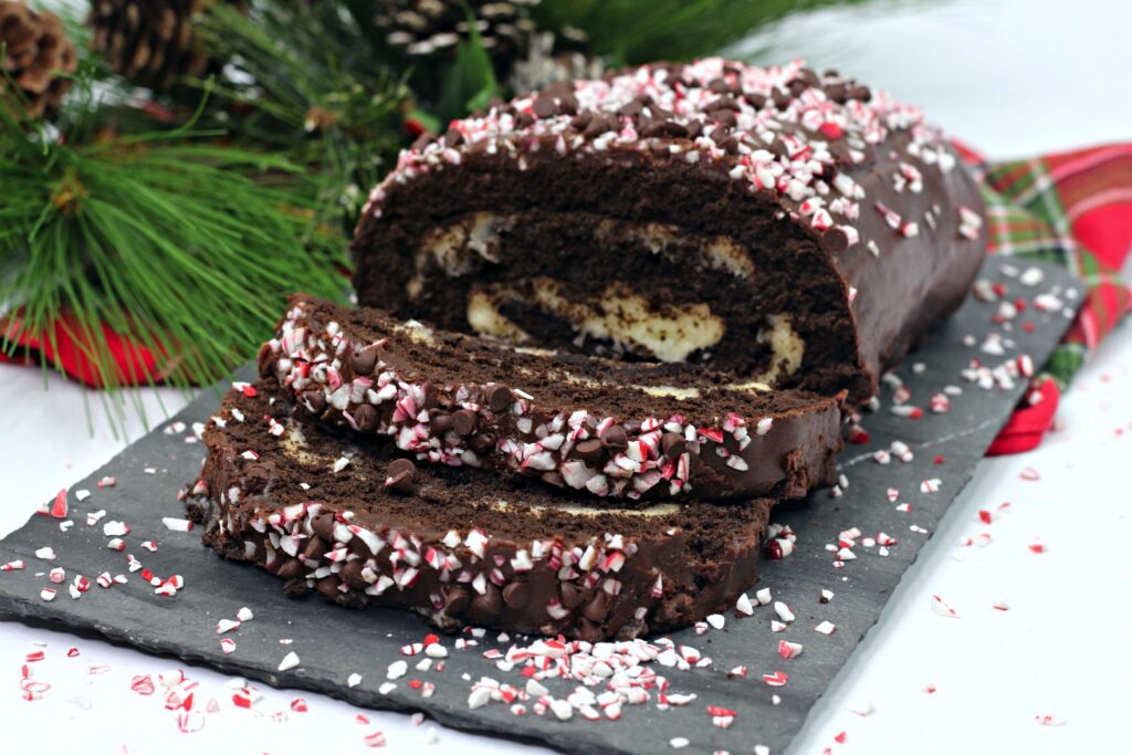A chocolate swiss roll cake, covered in a chocolate peppermint ganache and crushed peppermint candy.