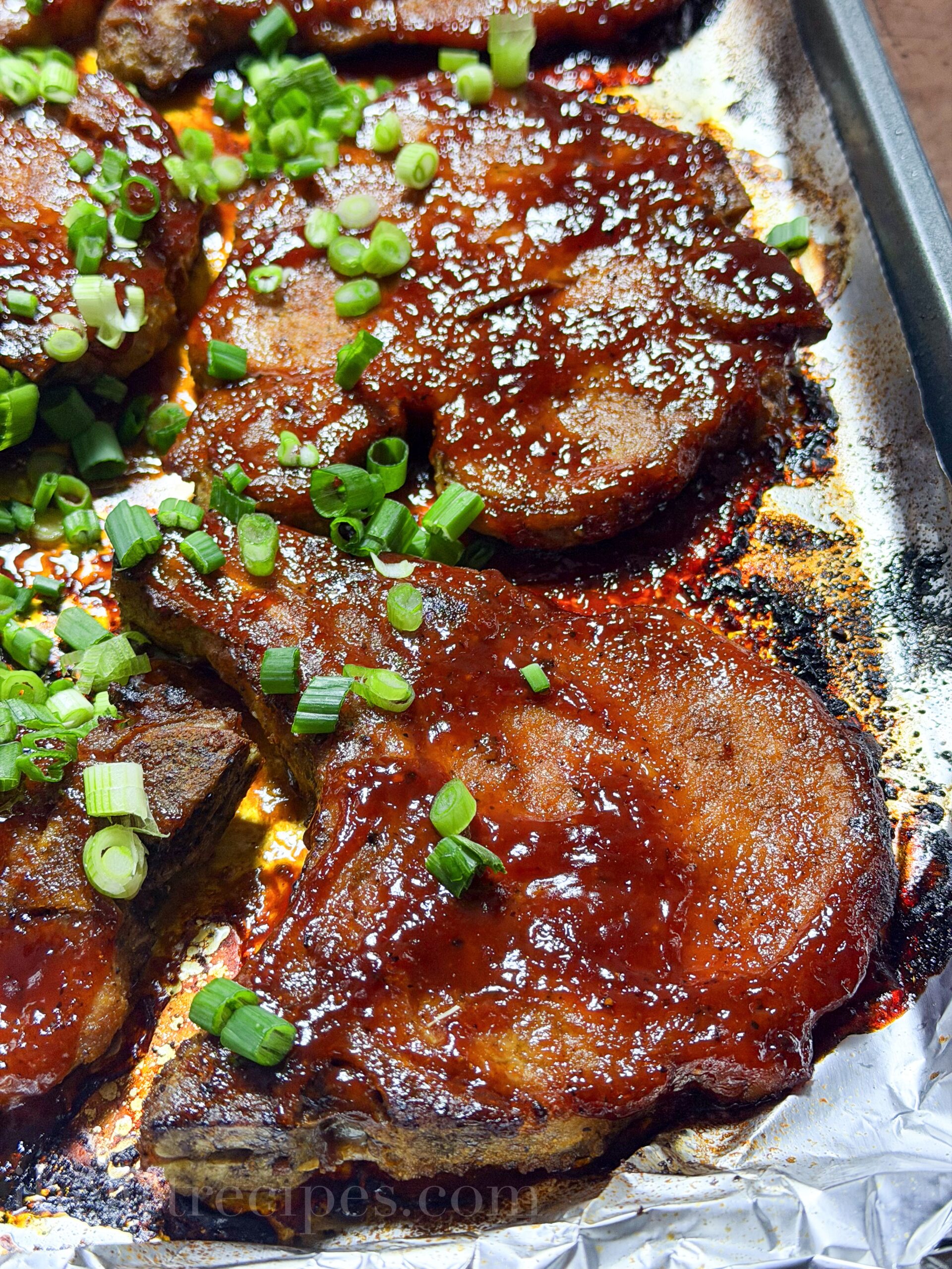 Oven baked barbecue pork chops topped with chopped green onions.