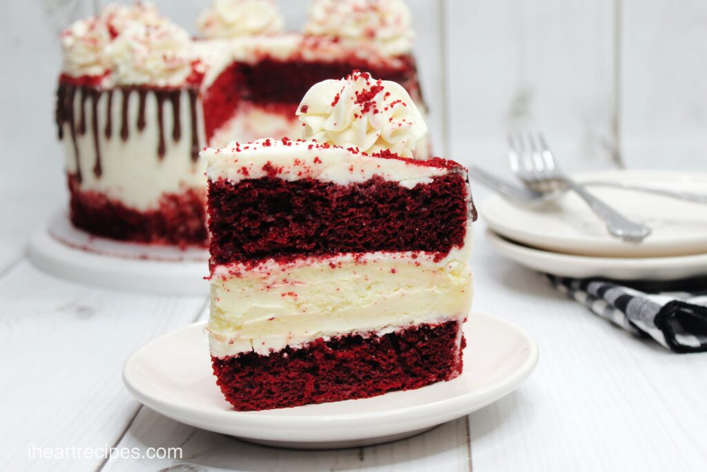 A thick slice of red velvet cheesecake, made with two layers of moist red velvet cake and a thick layer of vanilla cheesecake in the center.