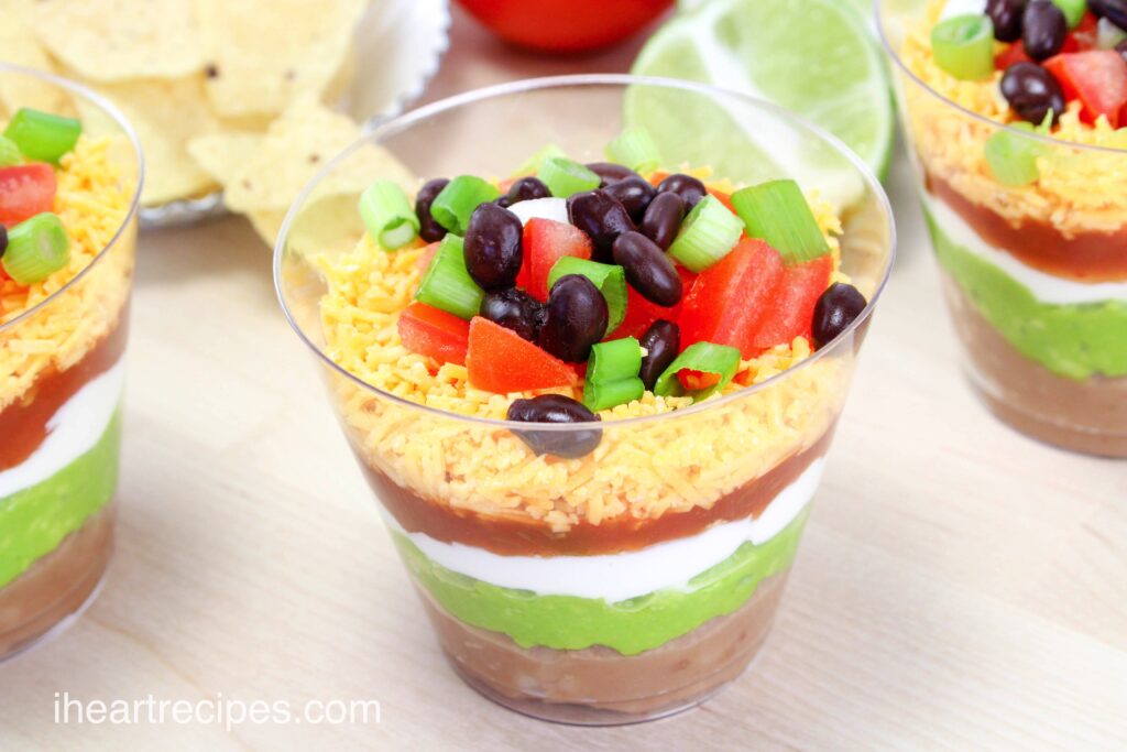 Individual nacho layer dip cups have six layers of yummy ingredients including refried beans, guacamole, sour cream, salsa, and cheese.
