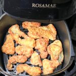Breaded catfish pieces in an air fryer basket.