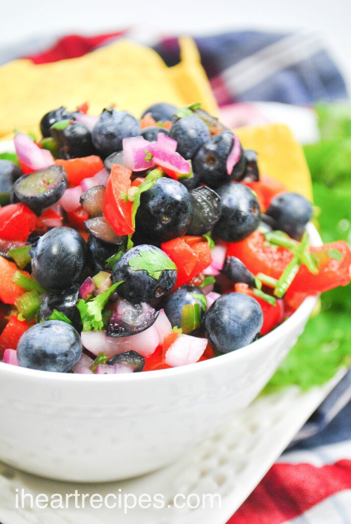 A close up image of a bowl of blueberry salsa -- juicy fresh blueberries mixed with sweet onions, peppers, lime, and cilantro.