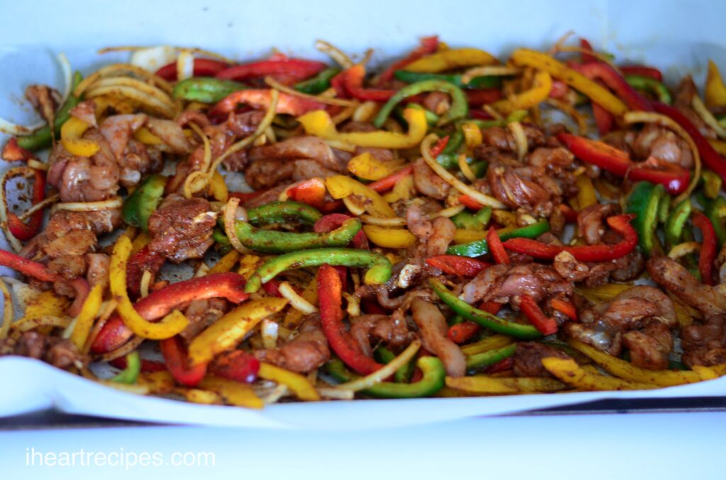 Flavorful chicken fajitas baked on a sheet pan -- a mix of red, yellow and green peppers, onions, and seasoned chicken strips.